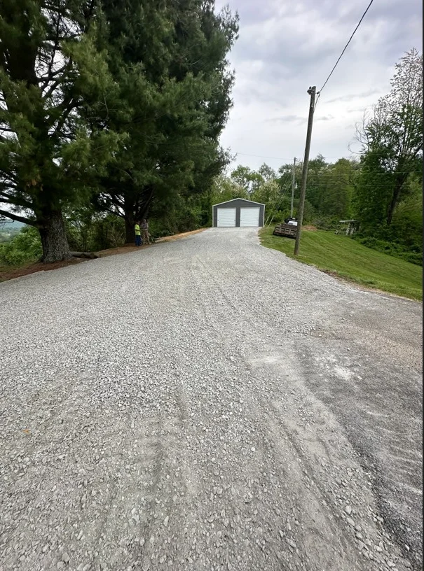 Newly installed gravel driveway with compacted stone base leading to garage structure