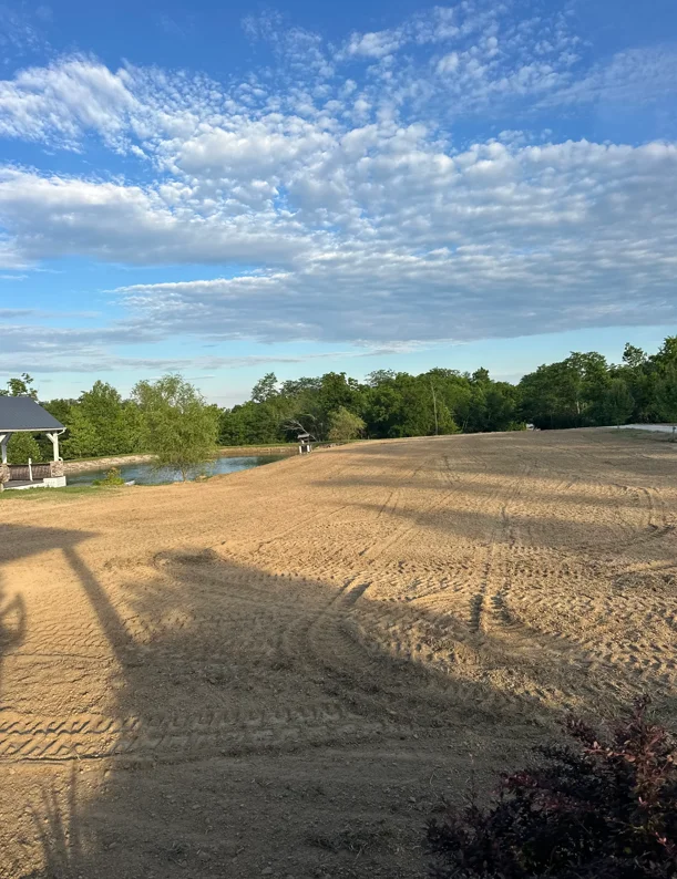 Excavated and graded dirt site with retention pond and cleared acreage