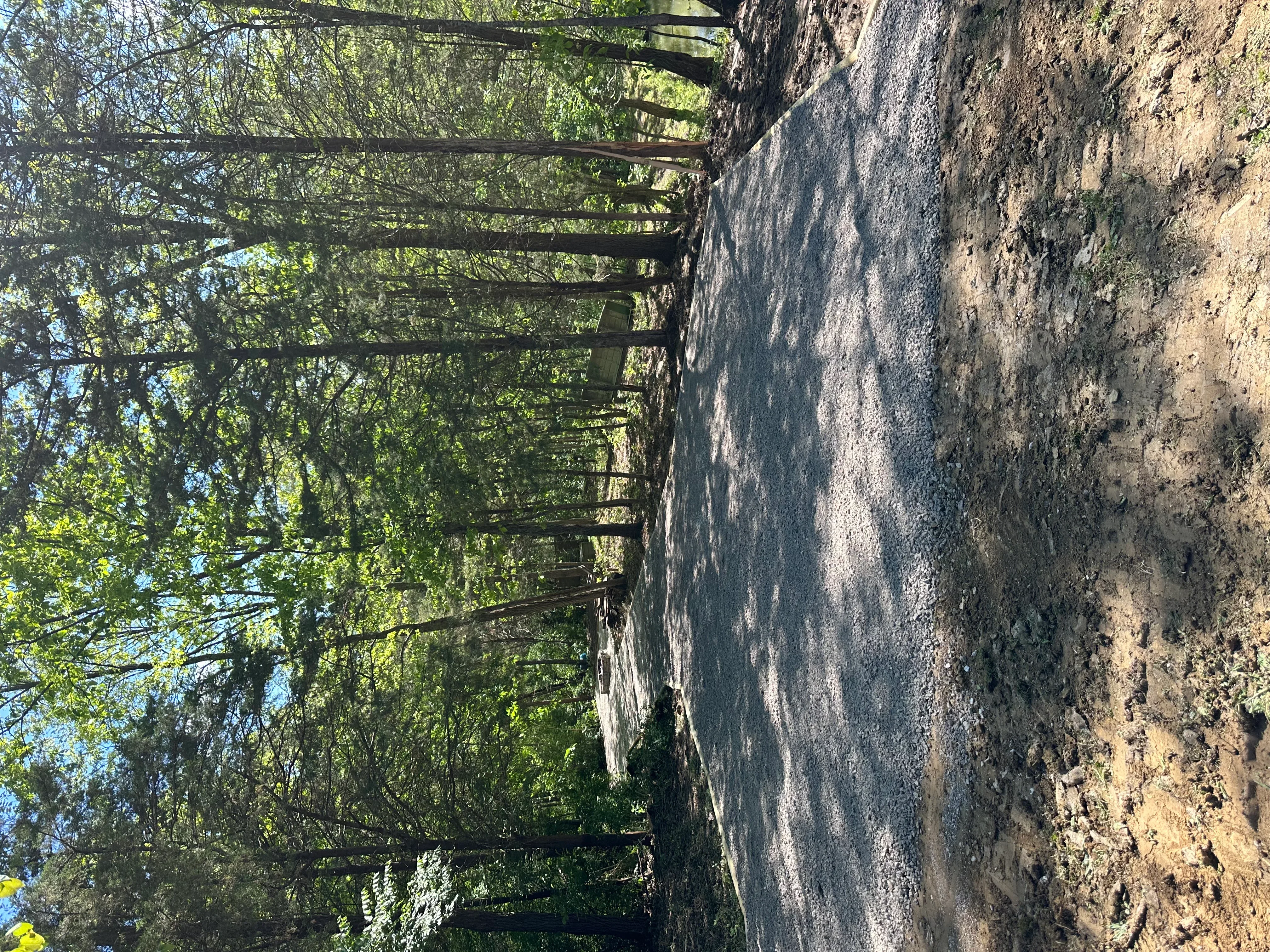 Excavated driveway site with metal culvert pipe and graded earth foundation