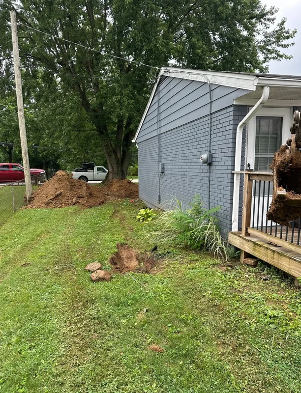 Residential yard grading with fresh topsoil pile and landscape preparation around home foundation
