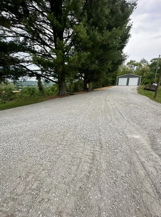 Compacted gravel driveway with mature trees and garage structure