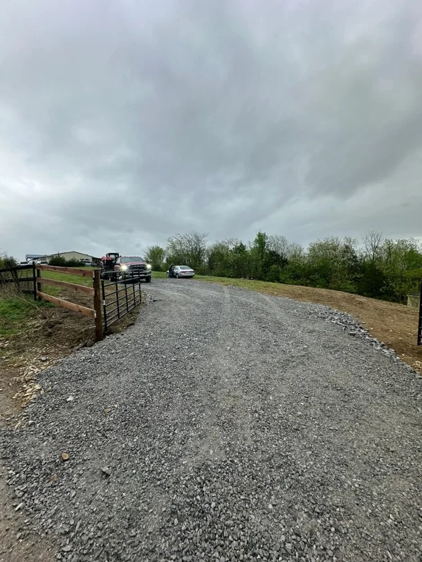 Newly installed gravel driveway with compacted stone base and metal gate entry