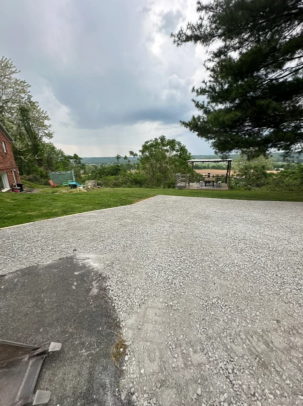 Newly installed gravel driveway with compacted crushed stone on sloped terrain